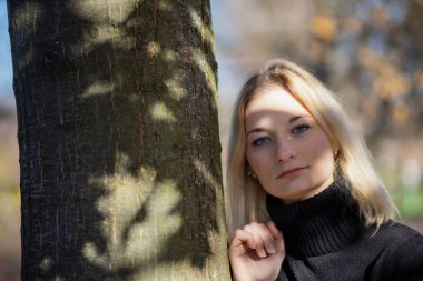 Uzun saçlı kız sonbahar parkında kameraya bakıyor. Yatay olarak. 