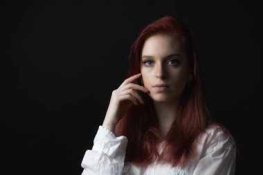 Güzel genç bir kadının kameraya bakarken yüzüne dokunuşunun sade bir portresi. Yatay olarak. 