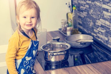 Gülümseyen küçük çocuk mutfakta poz veriyor. Yatay olarak. 