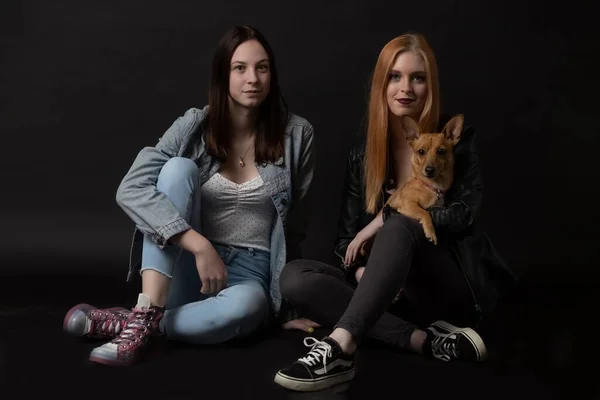Zwei Junge Frauen Sitzen Auf Dem Schwarzen Boden Und Halten — Stockfoto