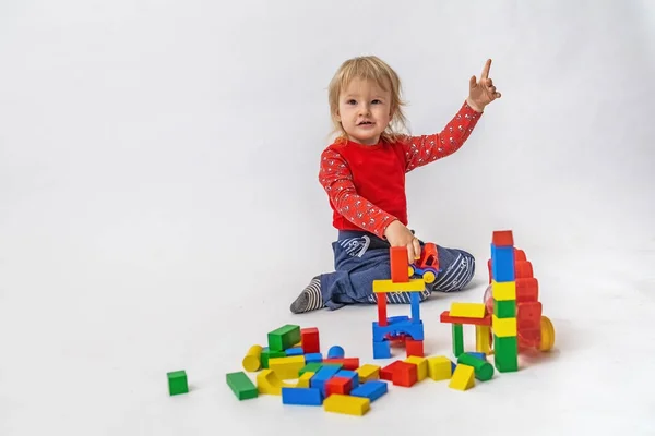 Милый Мальчик Поднятой Рукой Играет Разноцветными Деревянными Кубиками Горизонтально — стоковое фото