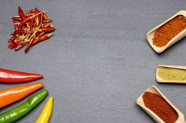 Masanın üzerinde değişik taze, kurutulmuş ve öğütülmüş biber çeşitleri var. Yatay olarak. 