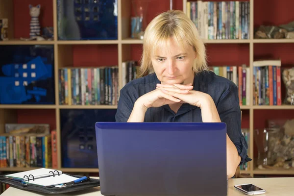 The middle aged woman is reading intently at a notebook — Stock Photo, Image