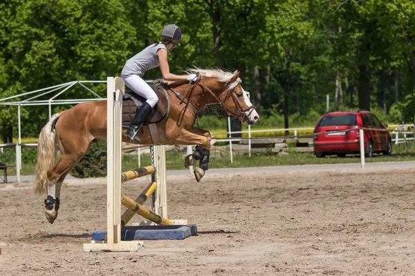 Vista laterale di horsewoman jumping — Foto Stock