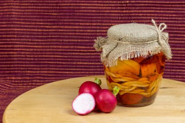 Jar of pickled cheese in oil with radishes