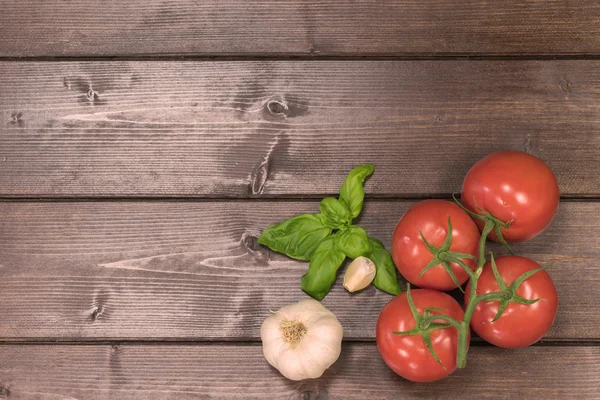 Tomatoes, garlic and basil on a wooden desk — Stock Photo, Image