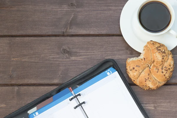 Managers diary and coffee cup on the wooden desk — Stock fotografie