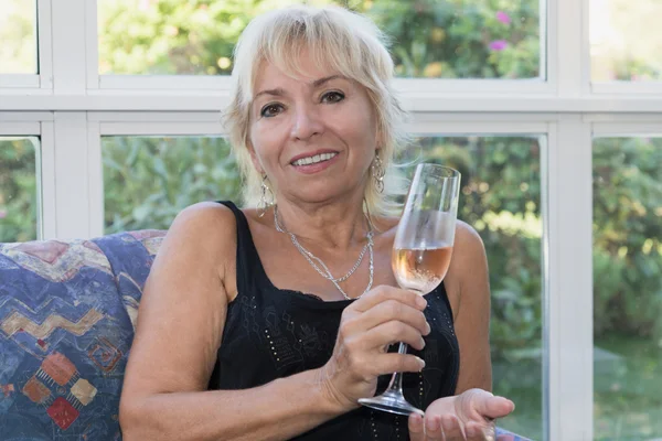 Senior mature blond woman is sitting on a couch — Stock Photo, Image