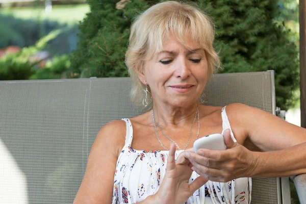 Mujer mayor rubia con teléfono inteligente al aire libre — Foto de Stock