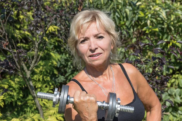 De senior blonde vrouw houdt een halter — Stockfoto