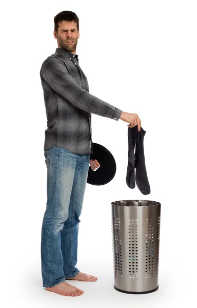 Young man putting dirty socks in a laundry basket