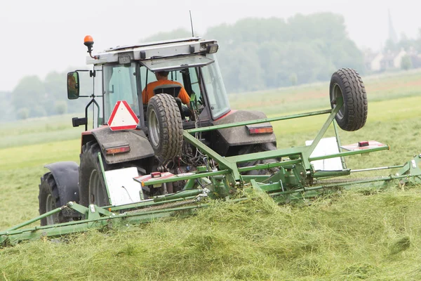 Boer gebruikt trekker te verspreiden hooi op het veld — Stockfoto