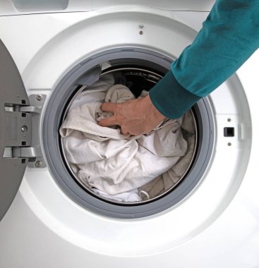 Çamaşır makinesini dolduran adam, temizlik zamanı.