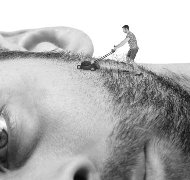 Minyatür çim biçme makinesi olan bir adam dev yüzünü tıraş ediyor.