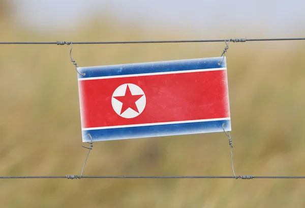 Border fence - Old plastic sign with a flag — Stock Photo, Image