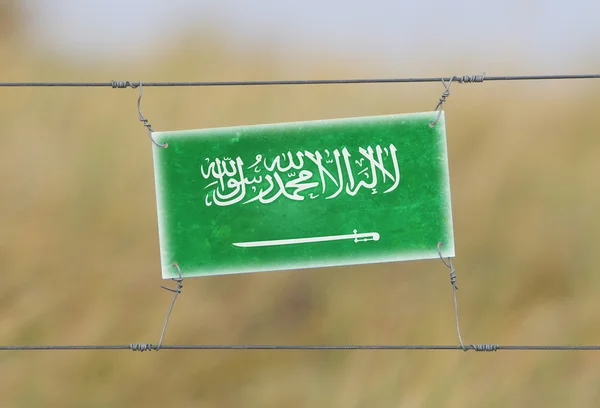 Border fence - Old plastic sign with a flag — Stock Photo, Image