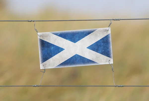 Border fence - Old plastic sign with a flag — Stock Photo, Image