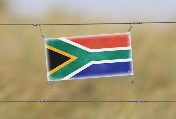 Border fence - Old plastic sign with a flag — Stock Photo, Image