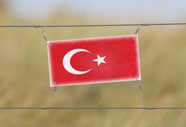 Border fence - Old plastic sign with a flag — Stock Photo, Image