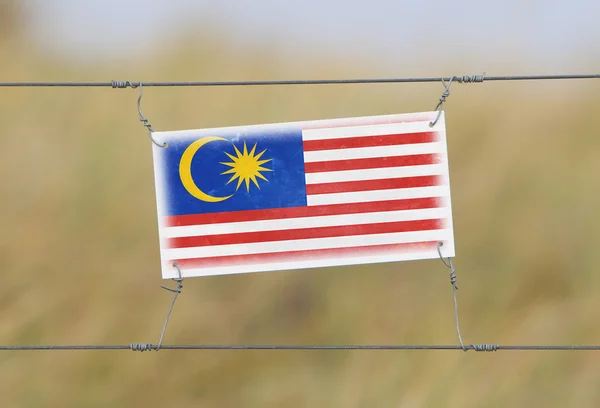 Border fence - Old plastic sign with a flag — Stock Photo, Image