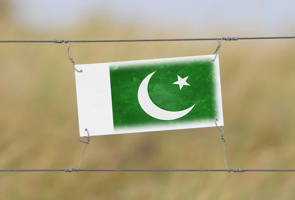 Border fence - Old plastic sign with a flag — Stock Photo, Image