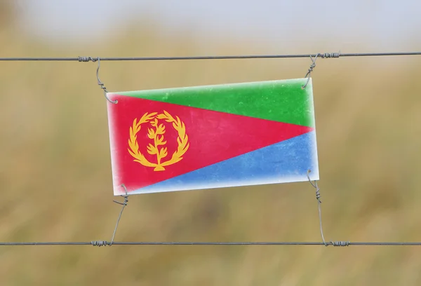 Border fence - Old plastic sign with a flag — Stock Photo, Image