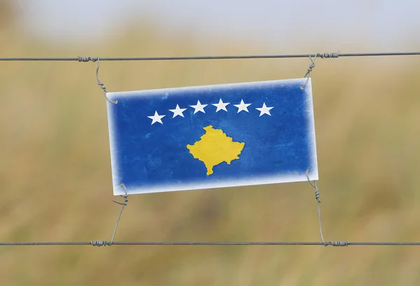 Border fence - Old plastic sign with a flag — Stock Photo, Image