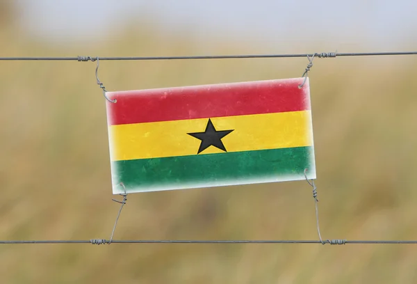 Border fence - Old plastic sign with a flag — Stock Photo, Image