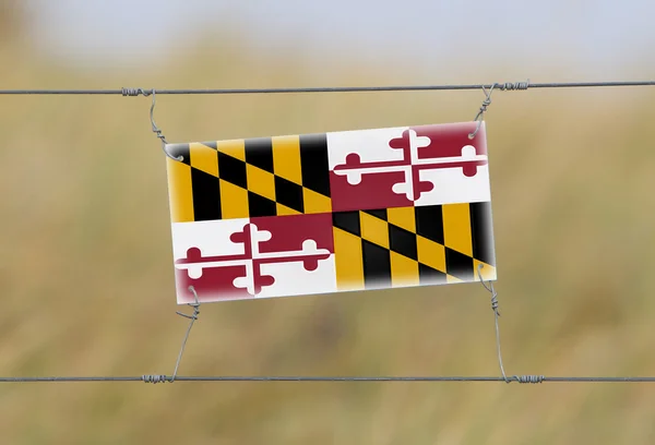 Border fence - Old plastic sign with a flag — Stock Photo, Image