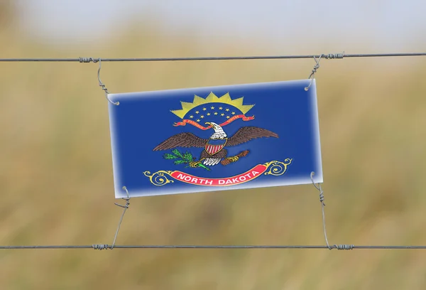 Border fence - Old plastic sign with a flag — Stock Photo, Image