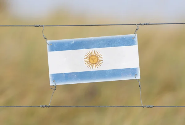 Border fence - Old plastic sign with a flag — Stock Photo, Image