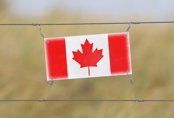Border fence - Old plastic sign with a flag — Stock Photo, Image