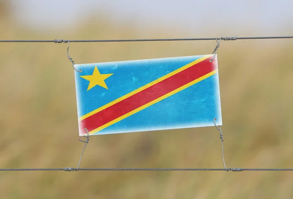 Border fence - Old plastic sign with a flag — Stock Photo, Image