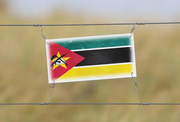 Clôture frontalière - Vieux panneau en plastique avec un drapeau — Photo