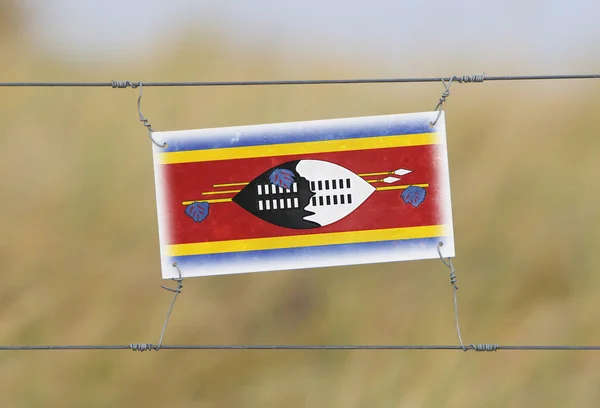 Border fence - Old plastic sign with a flag — Stock Photo, Image