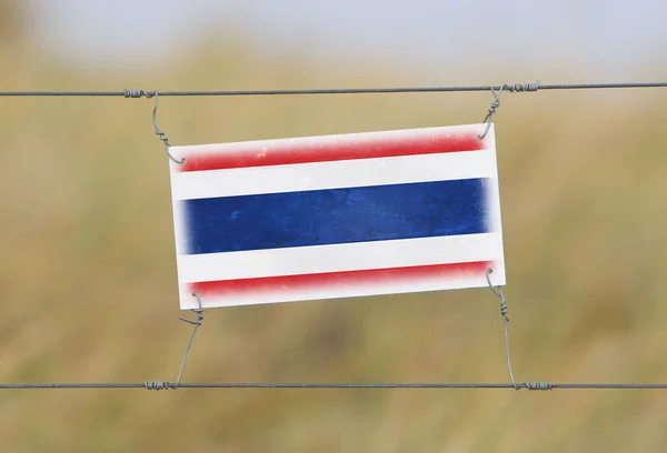 Border fence - Old plastic sign with a flag — Stock Photo, Image