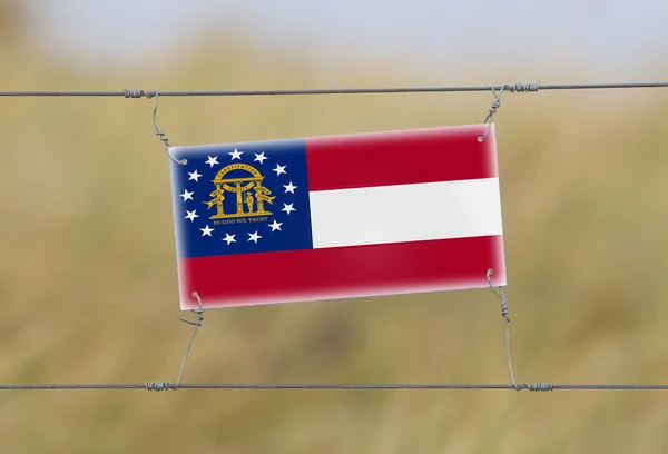 Border fence - Old plastic sign with a flag — Stock Photo, Image