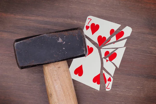 Martillo con una tarjeta rota, siete de corazones — Foto de Stock