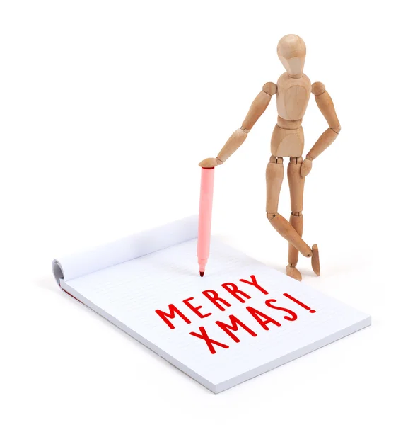 Wooden mannequin writing in scrapbook - Merry Xmas — стоковое фото