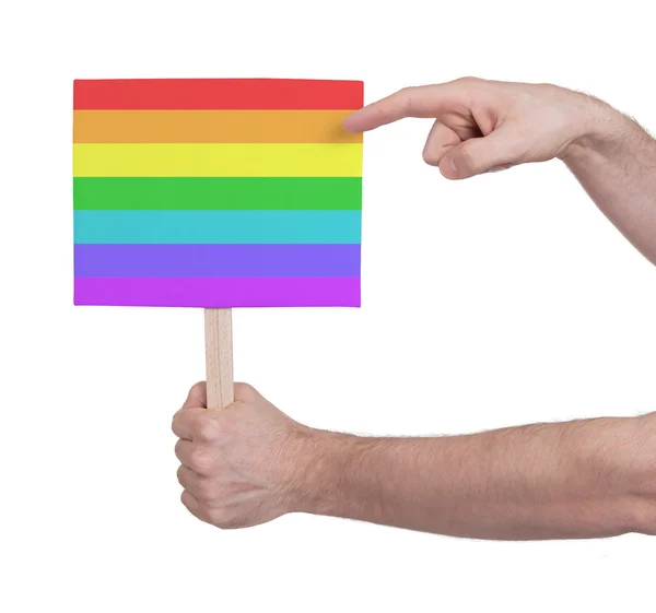 Mano sosteniendo una pequeña tarjeta - Bandera del arco iris — Foto de Stock