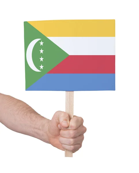Mão segurando cartão pequeno - Bandeira de Comores — Fotografia de Stock