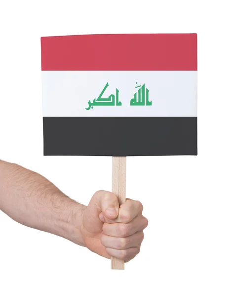 Mano sosteniendo una tarjeta pequeña - Bandera de Irak —  Fotos de Stock