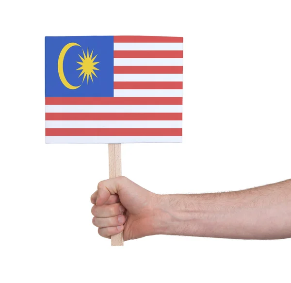 Mão segurando cartão pequeno - Bandeira da Malásia — Fotografia de Stock
