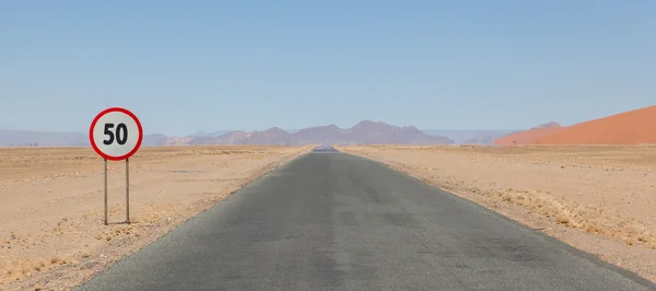 Señal de límite de velocidad en una carretera desierta en Namibia —  Fotos de Stock