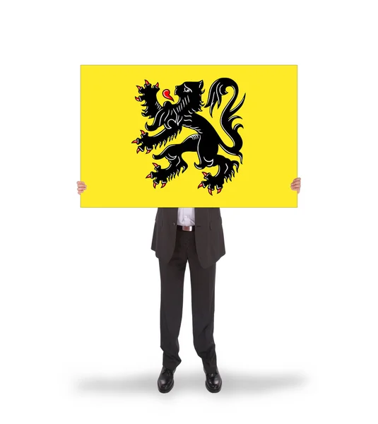 Hombre de negocios sonriente sosteniendo una tarjeta grande, bandera de Flandes —  Fotos de Stock