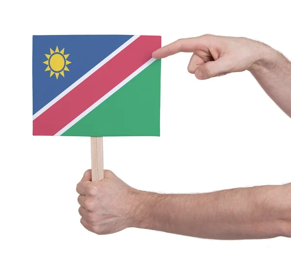 Mão segurando cartão pequeno - Bandeira da Namíbia — Fotografia de Stock