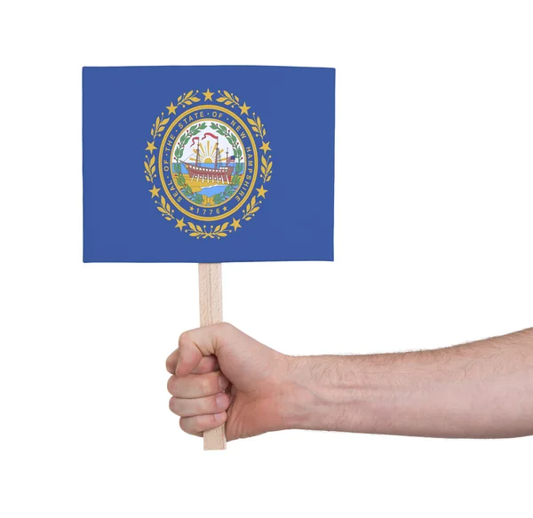 Hand som håller litet kort - flagga i New Hampshire — Stockfoto