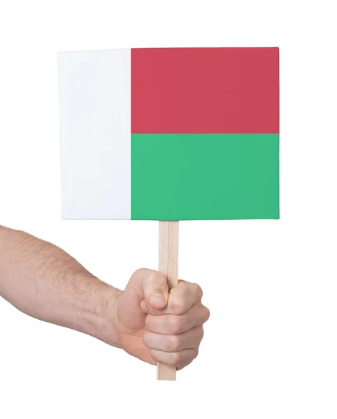 Mão segurando cartão pequeno - Bandeira de Madagascar — Fotografia de Stock