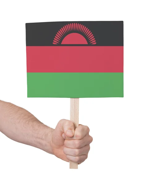 Hand som håller litet kort - flagga i Malawi — Stockfoto