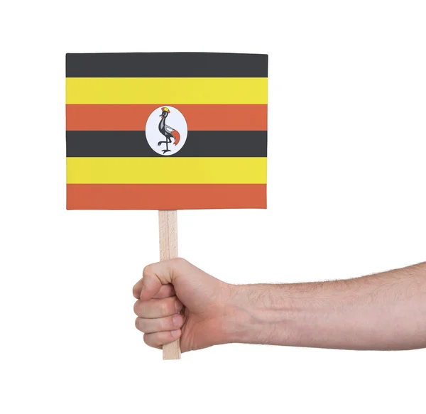 Mano sosteniendo una tarjeta pequeña - Bandera de Uganda —  Fotos de Stock